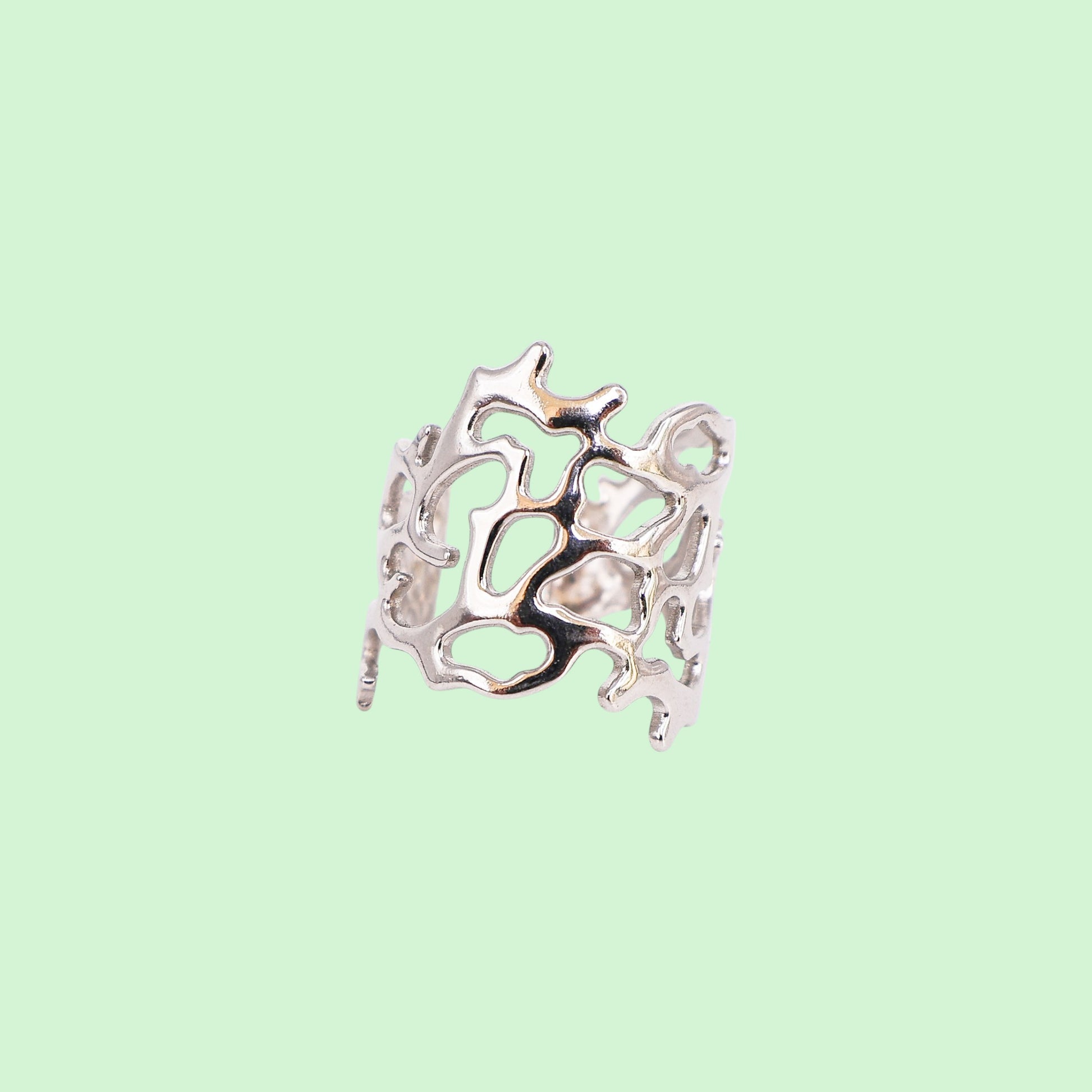 Silver ring with intricate coral design on a light green background